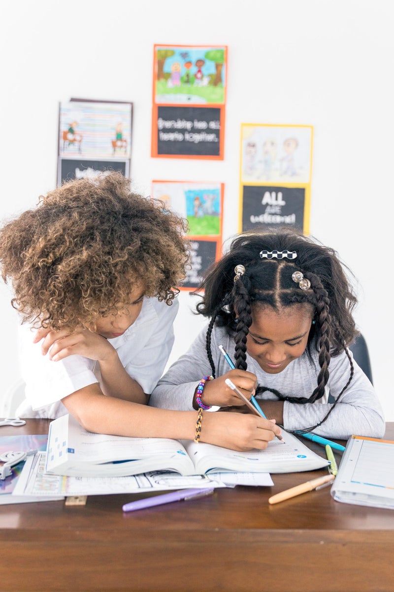 Two Black children looking at a book together