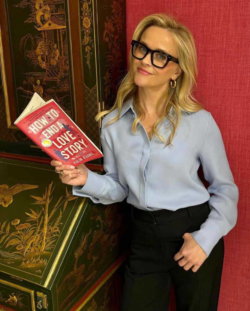 Reese Witherspoon holding a copy of How to End a Love Story by Yulin Kuang